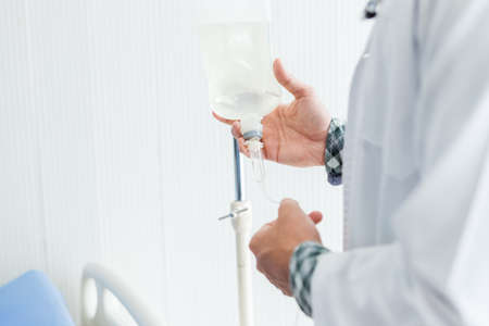 Close-up of Young man doctor therapeutic advising smiling face with stethoscope holding with saline...