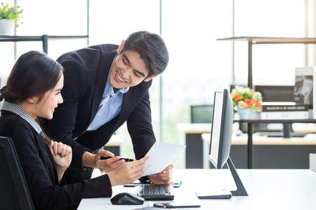 Happy of businesswoman and businessman partners discussing positive adult business working together with computer on wooden table and ideas at meeting in office background.の写真素材
