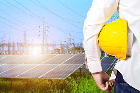 Industry worker or engineer working with power solar panel with High voltage post in blue sky,Alternative energy conceptの写真素材