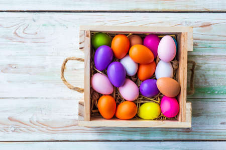 Easter holiday concept,Colorful Easter eggs in basket on white pastel color rustic wood background...