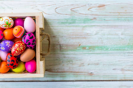 Easter holiday concept,Colorful Easter eggs in basket on white pastel color rustic wood background with space.の写真素材
