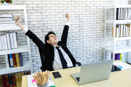 Happy of successful asian young businessman on laptop computer, Smartphone and pencil on notebook In...
