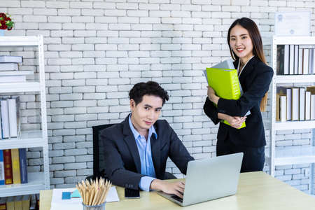 Company executive Young Asian businessman and coaching personal secretary assistant businesswoman partners while working together with hold file folder and strategy in business profit in office.の写真素材