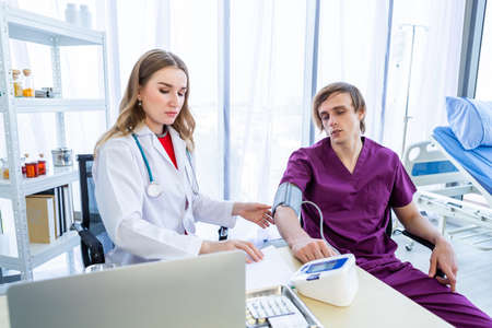 female doctor with measuring the pressure to the arm of a man patient wear arm with Digital pressure gauge for better healing In the room hospital background.の写真素材