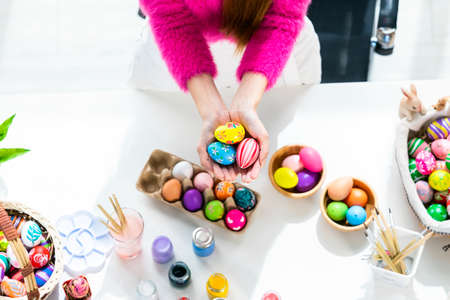 Easter holiday concept,Close up of Happy Asian Young woman holding with colorful Easter eggs on white wooden table background in top viewの写真素材