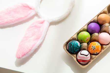 Easter holiday concept,colorful Easter egg in egg box,basket Easter eggs and bunny ears on white...