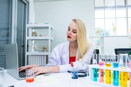 portrait of a female researcher carrying working with laptop computer and out research in a chemistry lab scientist holding test tube with sample in Laboratory analysis backgroundの写真素材