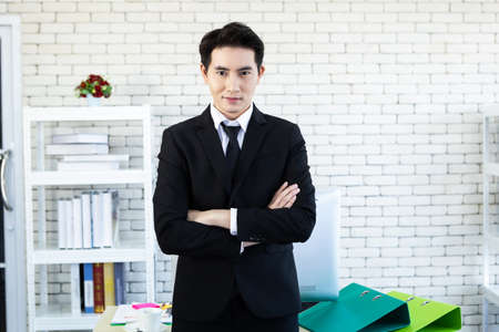 Portrait of a cheerful mature asian young businessman wear a business suit of man in blue jacket and blue shirt looking at the window In the office room background.の写真素材