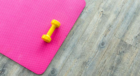 yellow dumbbells on an empty pink rubber floor on wooden floor background,top view with copy space health and exercise conceptの写真素材