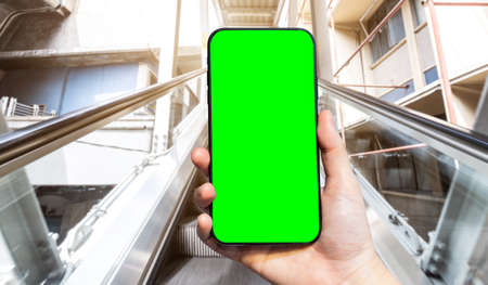 Close-up of female use Hand holding smartphone with empty blank green screen blurred images touch of...
