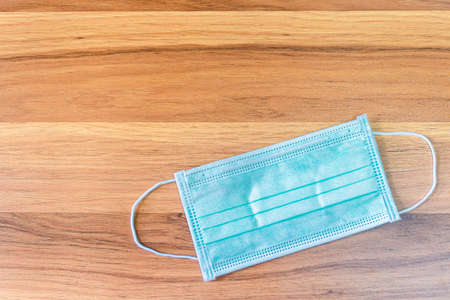 Blue Protective disposable medical mask on wooden background,Top view office table,Concept of...