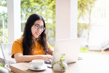 Happy of asian freelance people business female casual working with laptop computer with coffee cup and smartphone in coffee shop like the background,communication conceptの写真素材