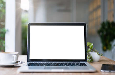 Mockup of laptop computer with empty screen with coffee cup and smartphone on table of the coffee shop background,White screenの写真素材