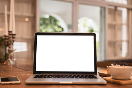 Mockup of laptop computer with empty screen with coffee cup and smartphone on table of the coffee shop background,White screenの写真素材
