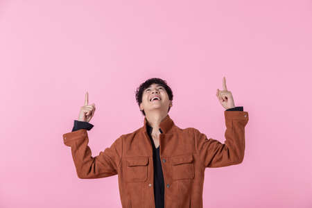 Asian a man handsome young pointing with two hands and fingers to the side eyes looking at camera in love isolated on pink blank copy space studio background.の写真素材