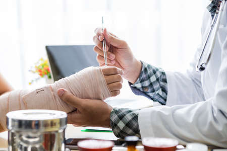 man doctor of checking splint the arm of female patient hand due to with her arm broken for better healing sit in a wheelchair In the room hospital background.の写真素材