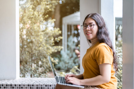 Happy of asian freelance people business female casual working with laptop computer sitting on a bench in coffee shop like the background,communication conceptの写真素材