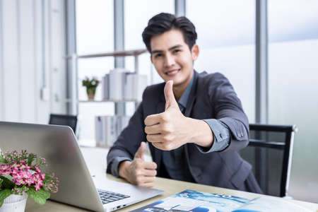 asian young businessman see a successful business plan on the laptop computer and document paper...