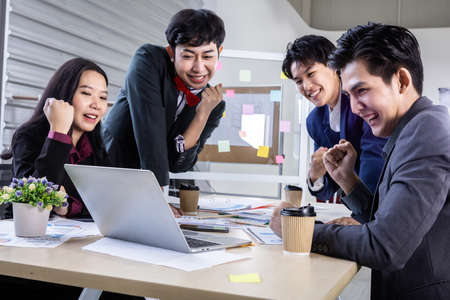 Successful happy workers Group of asian business people with diverse genders (LGBT) see a successful business plan on the laptop computer in the meeting room at officeの写真素材