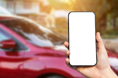 Close-up of female use Hand holding smartphone blurred images touch of Abstract blur of headlight ,window of red car outdoor background.の写真素材