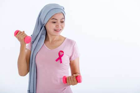 a asian woman in with pink breast cancer awareness ribbon hold a dumbbell isolated on pink blank copy space studio background,healthcare,medicine conceptの写真素材