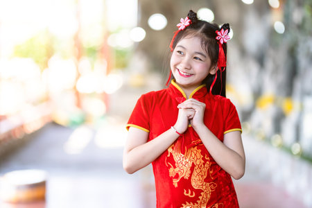 Portrait beautiful smiles Cute little Asian girl wearing red traditional Chinese cheongsam decoration for Chinese New Year Festival at Chinese shrineの写真素材