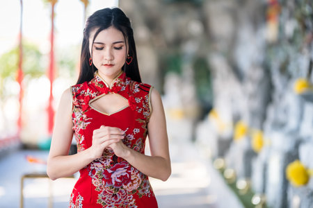 Portrait beautiful smiles Asian young woman wearing red traditional Chinese cheongsam decoration for Chinese New Year Festival at Chinese shrine in Thailandの写真素材