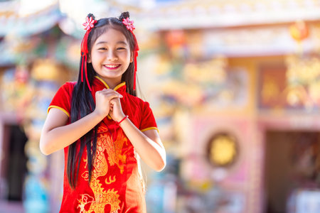 Portrait beautiful smiles Cute little Asian girl wearing red traditional Chinese cheongsam decoration for Chinese New Year Festival at Chinese shrineの写真素材