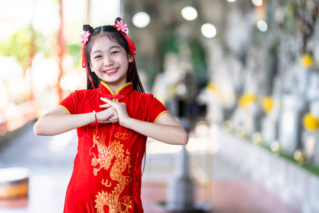 Portrait beautiful smiles Cute little Asian girl wearing red traditional Chinese cheongsam decoration for Chinese New Year Festival at Chinese shrineの写真素材