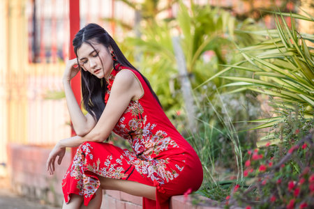 Portrait beautiful smiles Asian young woman wearing red traditional Chinese cheongsam decoration for Chinese New Year Festival at Chinese shrine in Thailandの写真素材