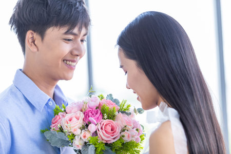 Valentine's day concept,asian Young happy sweet couple holding bouquet of red and pink roses After lunch In a restaurant background,Love story coupleの写真素材