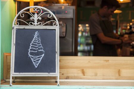 A chalkboard sign showing an ice-cream cone in a shop windowの写真素材
