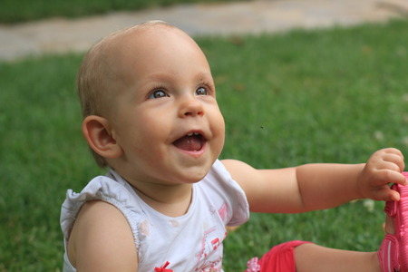 little girl smile while sitting on the grassの写真素材
