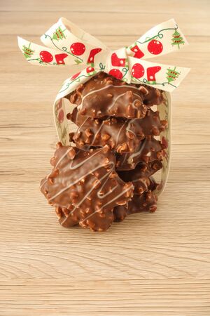 A stack of star shaped German Gingerbread with almonds decorated with a cute Christmas ribbon isolated on light brown wooden background.の写真素材