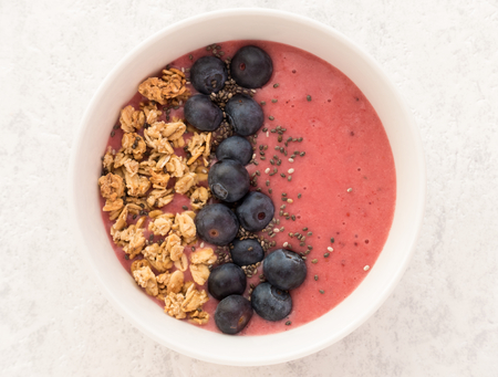 Closeup of a homemade Berry Smoothie with Granola and Blueberries on white textured background.の写真素材