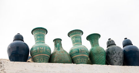 Moroccan ceramic vases, pots and vats in green and blue colors standing on a wall outside with copy space.の写真素材