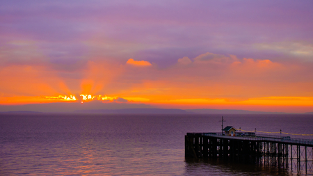 Colorful sunrise with sea, Penarth Pier and sky background in golden and magenta colors.の写真素材