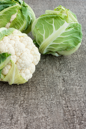 Arrangement of three whole cauliflowers on dark brown background.の写真素材