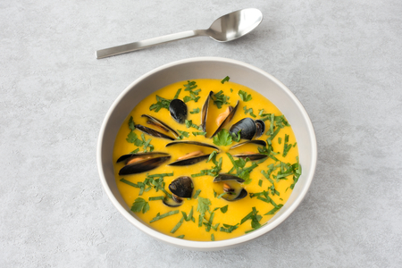 Mussel and Butternut squash soup in a bowl on gray background with copy space. の写真素材