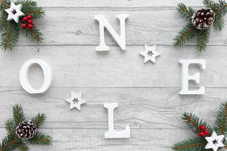 Noel written with white wooden letters on wood background decorated with fir tree twigs, wooden stars, snowy pine cones and red berries. の写真素材