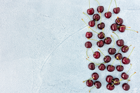 Sweet red cherries on beautiful blue cement background with lots of copy space.の写真素材
