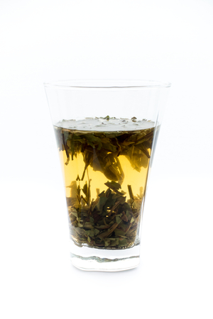 Cold brew white tea concentrate and tea leaves in a drinking glass on white background.の写真素材