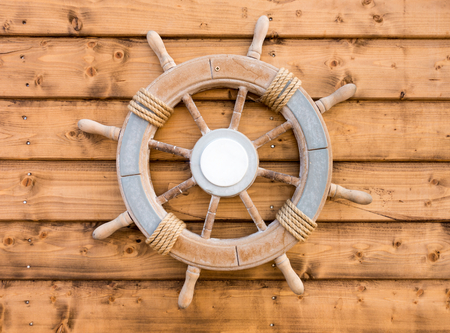 Nautical wooden boat ship steering wheel on brown wood planks.の写真素材