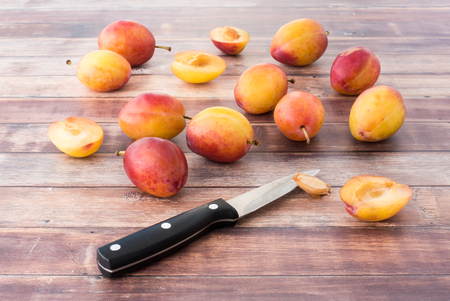 Whole and halved British Victoria plums on dark brown rustic wood panel background.の写真素材