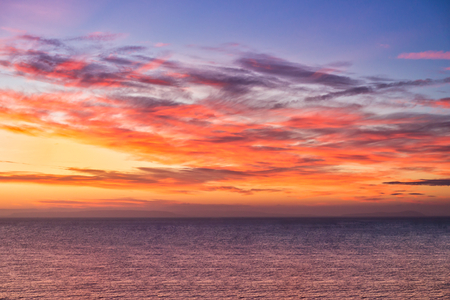Dramatic sunrise over the sea in vibrant yellow, orange, pink and purple colors.の写真素材