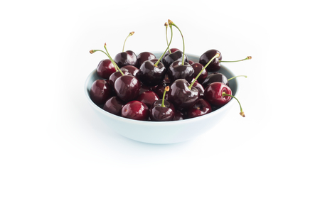 Close-up of a blue bowl filled with fresh cherries isolated on white background. Angled view.の写真素材