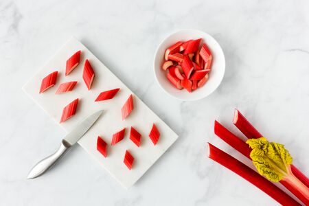 Forced Rhubarb on marble cutting board and in porcelain bowl on white marble background with copy space. Top view.の写真素材