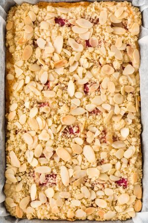 Top view of homemade rhubarb crumble cake in a baking tray lined with parchment paper.の写真素材