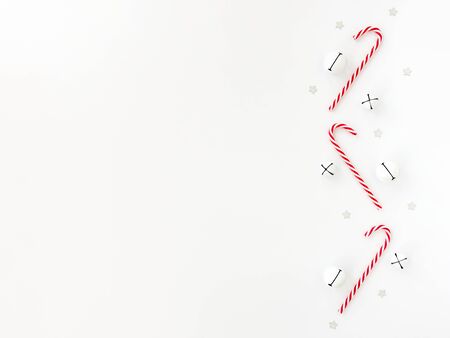 Christmas border with white jingle bells, candy canes and silver star confetti isolated on white. Top view.の写真素材