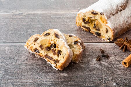 German stollen, Christstollen, with marzipan on dark brown rustic, weathered wood panel background with copy space. Angled view.の写真素材